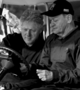 Chrétien is holding the wheel where is sitted Bill Clinton.