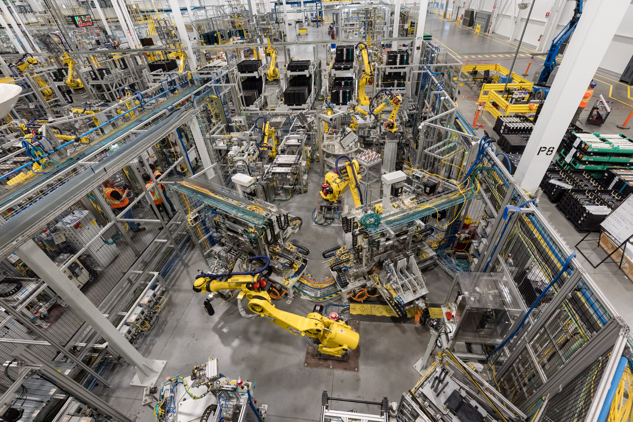 An arial view of the factory floor shows a busy scene of robotic arms and other machinery.