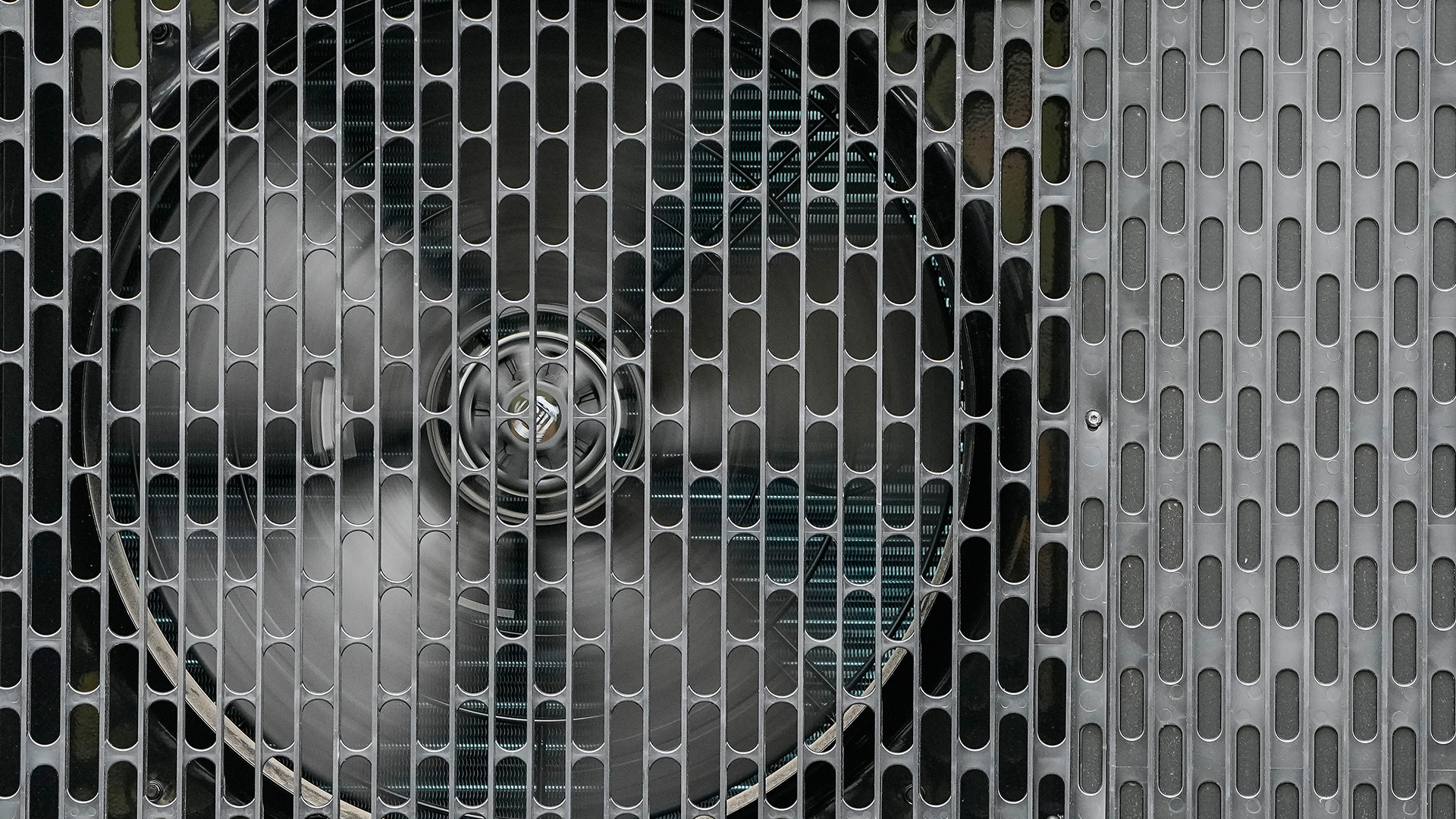 A close-up view of the grill and fan of a heat pump.