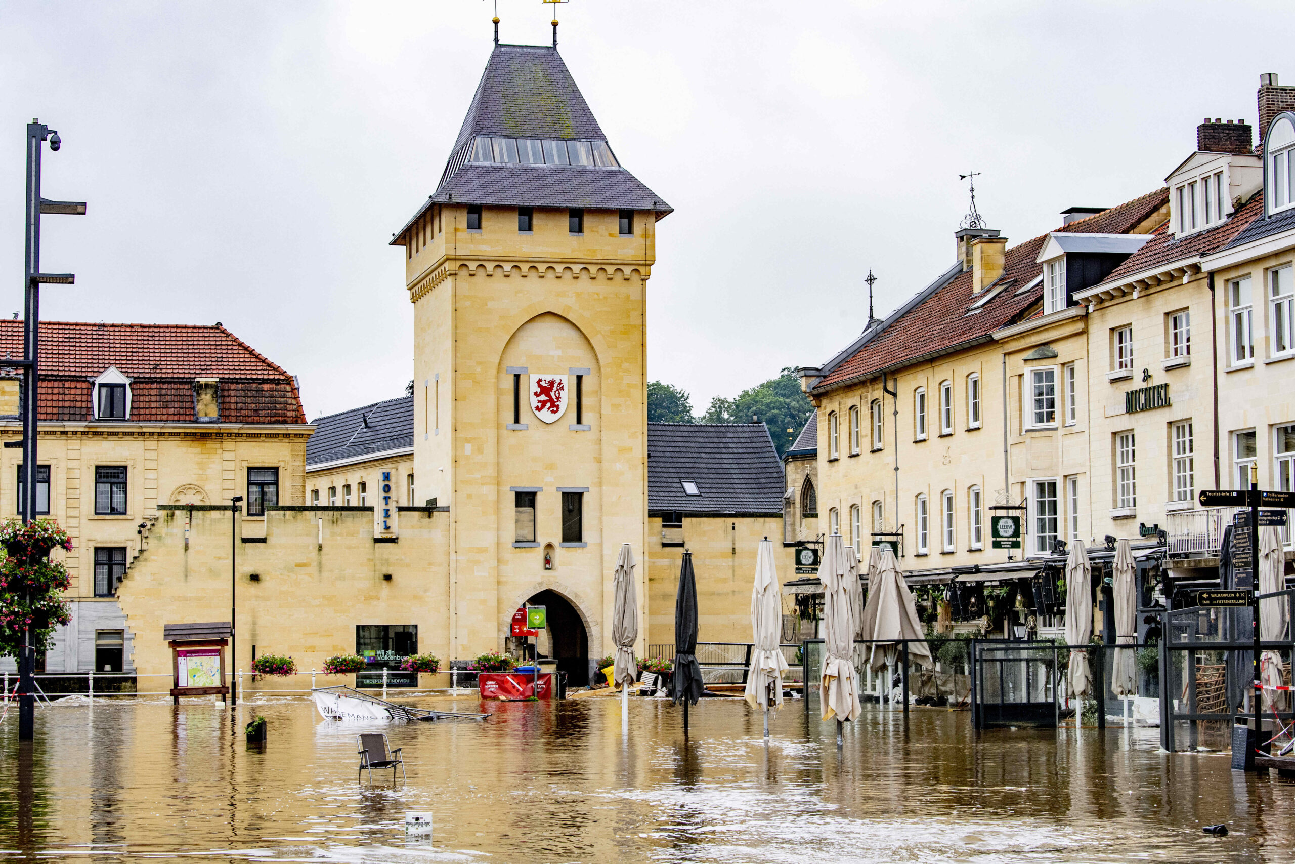 Water sits at table level on a street lined with sandstone buildings with tile roofs.