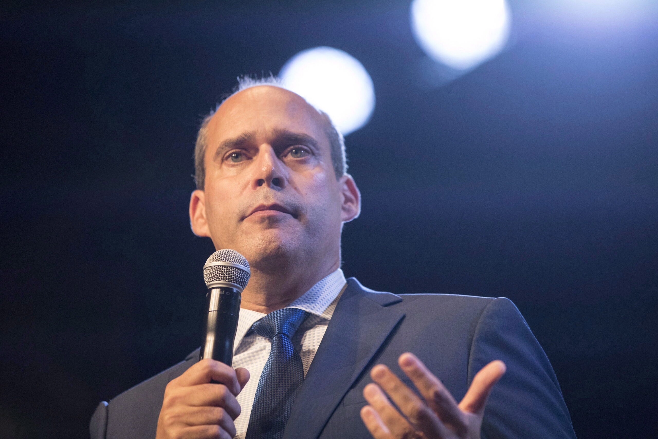 Gros plan sur Guy Caron, qui s’adresse à une foule, un micro à la main.