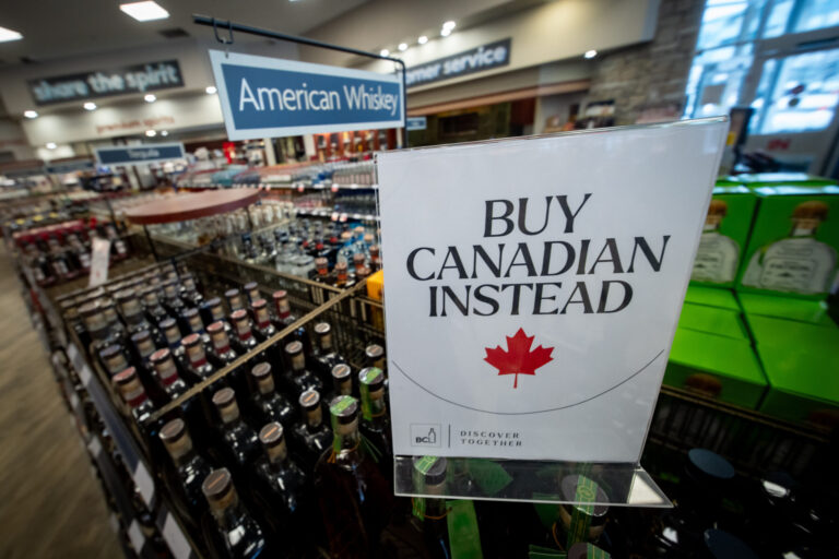 A “buy Canadian instead” sign is in front of a sign for many rows of “American liquor.”