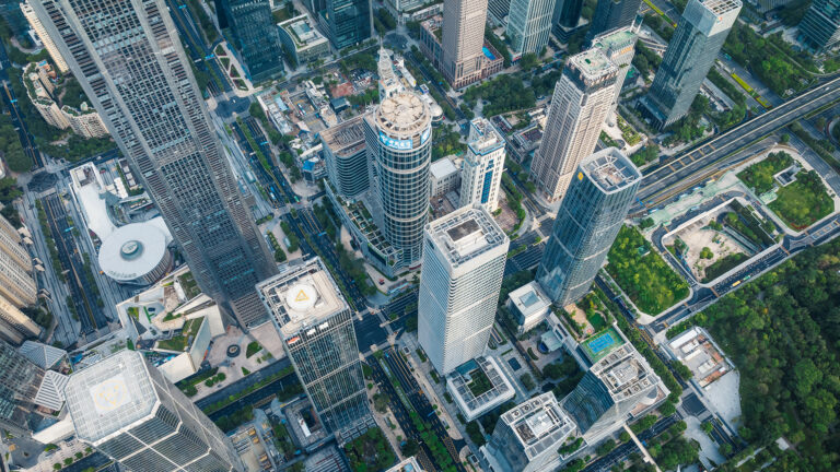Aerial view of the city showing a district with skyscrapers, multi-lane streets and green spaces.