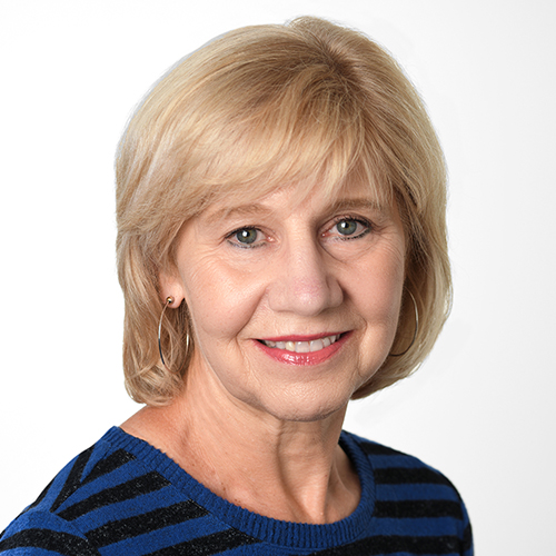 Headshot of Kathryn, who is white and has short, straight blond hair. She is smiling, and is wearing a shirt with blue and black stripes.