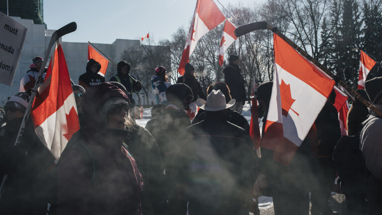 Several people carrying Canadian flags during a protest.