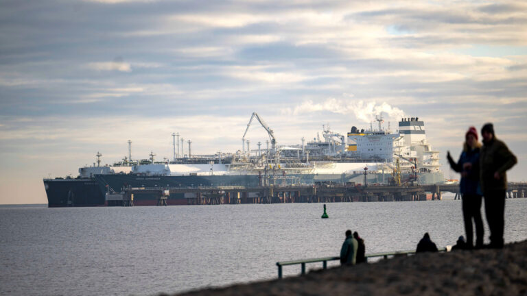 The tanker is docked alongside another ship at a jetty. 