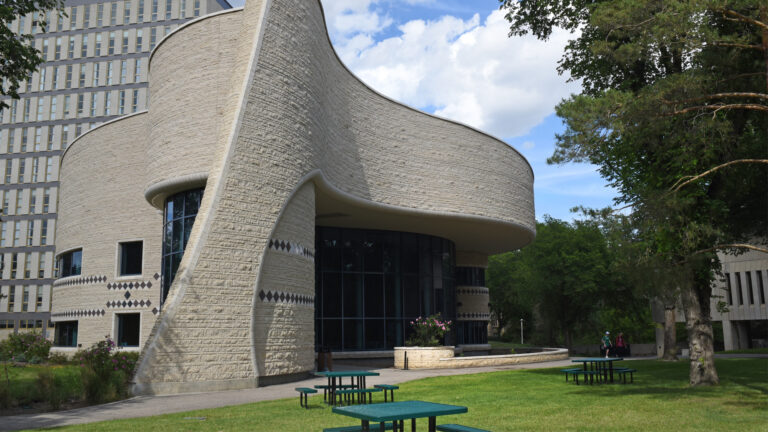 The building is several storeys high with walls that curve into a couple of semi-circles. It’s covered in textured concrete.