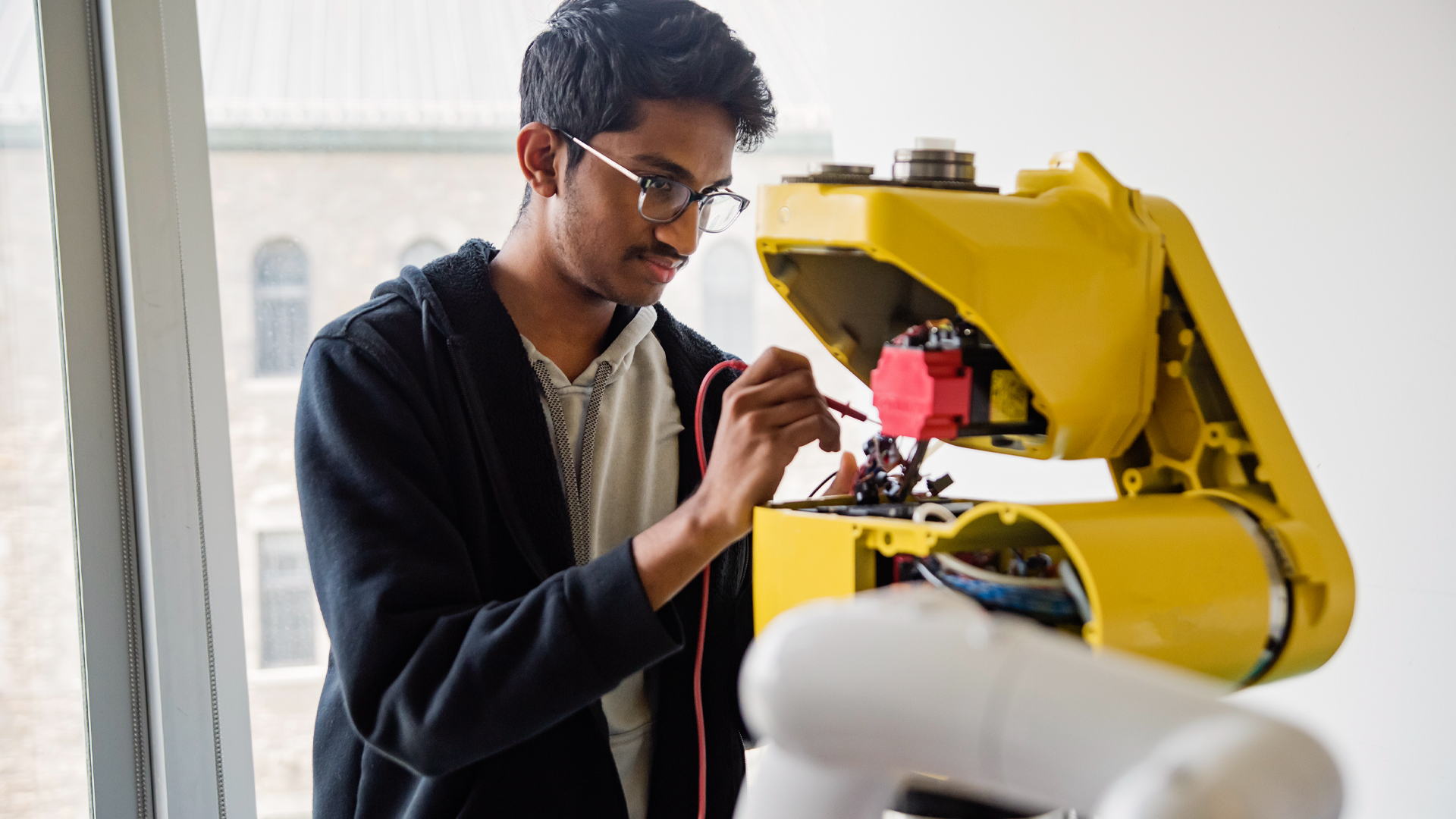A man uses a probe on a yellow machine.