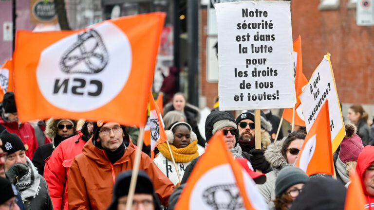 Des dizaines de travailleurs portant des pancartes et des drapeaux à l'effigie du syndicat.