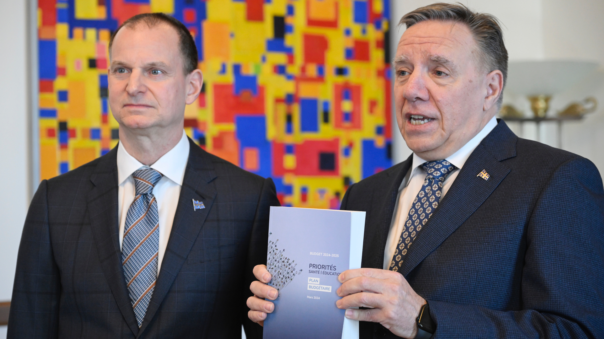 Quebec Finance Minister Eric Girard stands with Premier François Legault as he holds up the province's 2024 budget.