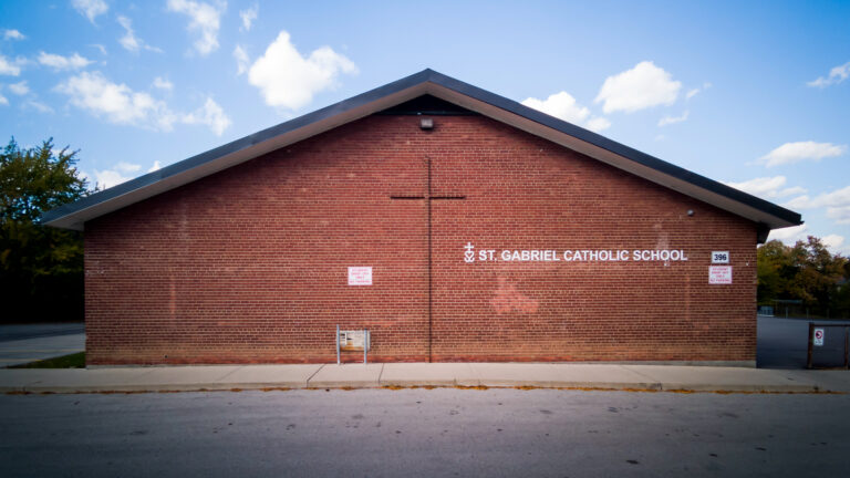 A large holy cross is depicted in the brick pattern of the one-storey school.