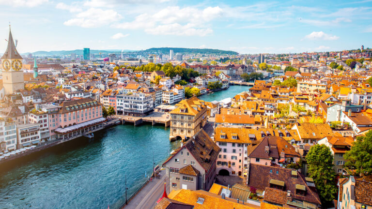 A river runs through the city, lined with tightly packed homes and buildings about four or five storeys high.