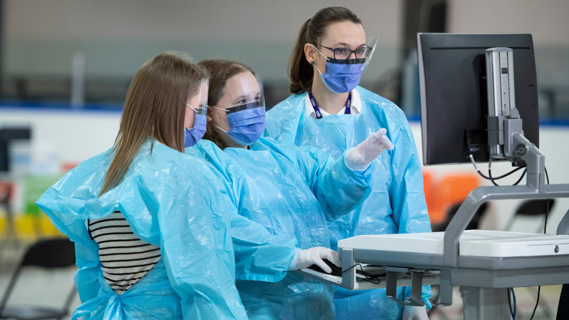 Several health care professionals standing behind computer screen.