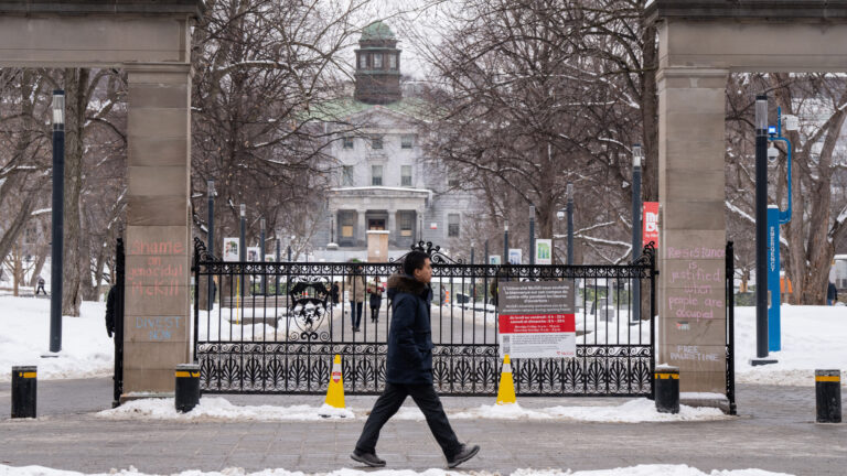 Un étudiant tout habillé de noir passe devant l’entrée du campus de l’Université McGill, à Montréal par une journée d’hiver.