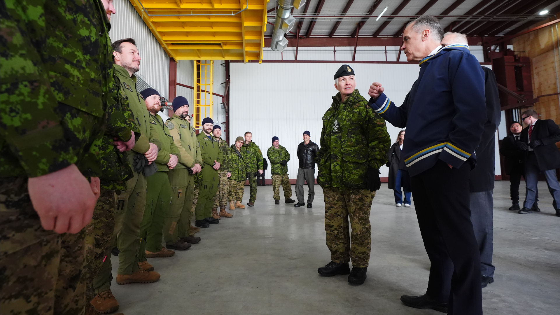 Mark Carney is wearing a blue traditional Inuit pullover called the atigi while speaking to soldiers wearing their green uniforms.