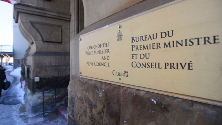 Sur un mur extérieur en pierres taillées, une plaque arborant les armoiries du Canada indique l’entrée vers le bureau du premier ministre et du Conseil privé.
