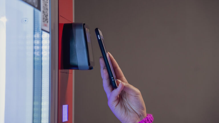 Close up view of woman paying for purchase at snack vending machine using smartphone.