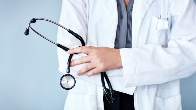 Photo de studio recadrée d'un médecin tenant un stéthoscope sur fond bleu