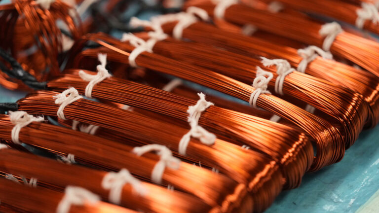 A dozen bundles of copper wire tied together with white string.