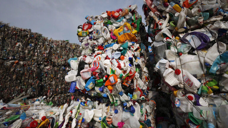 A huge pile of plastic containers of various shapes and colors is compacted in a landfill for export.