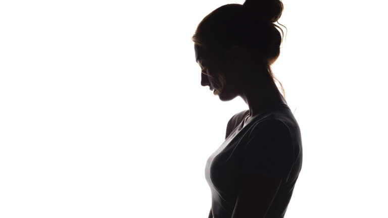 Silhouette of a young woman in a sleeveless shirt, her hair tied in a bun.