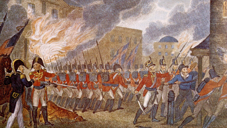 Une ligne de tuniques rouges défilant devant un bâtiment en flammes.