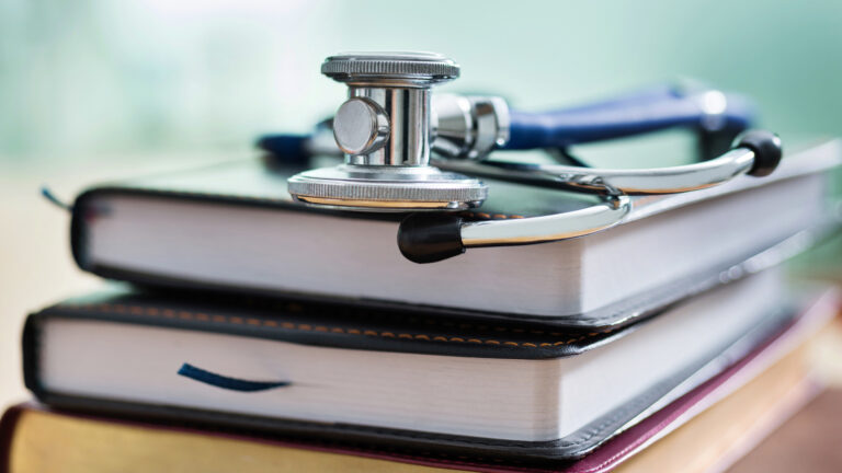 A stack of books with a stethoscope on top.