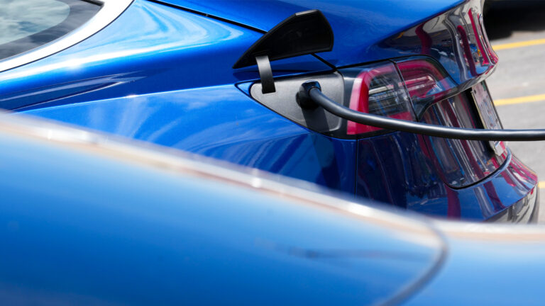 A blue electric vehicle with a black cable attached to it.