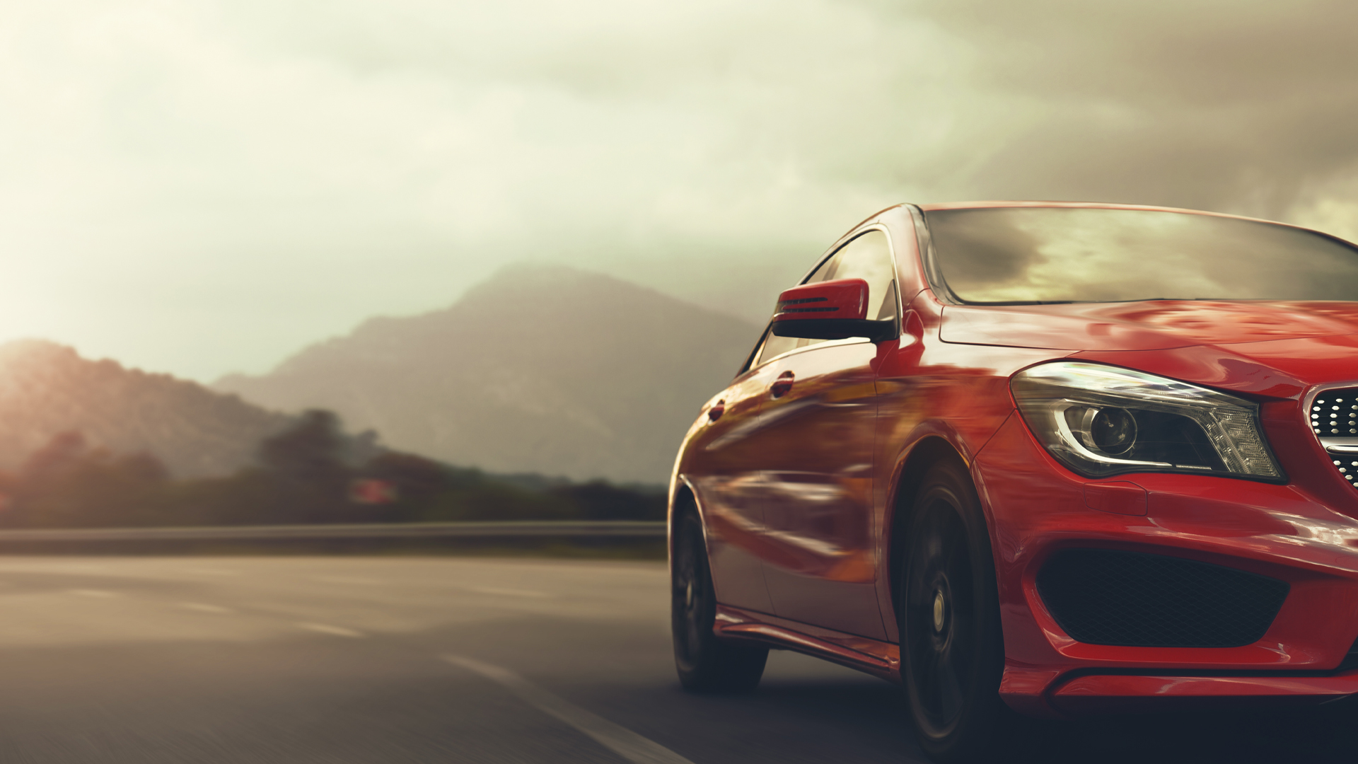 A red car drives on a winding road through a mountains.