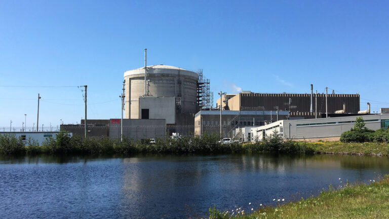 A beige cluster of industrial buildings sits next to the water’s edge.