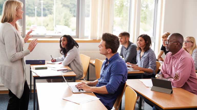 A woman leads a small classroom of adult students.