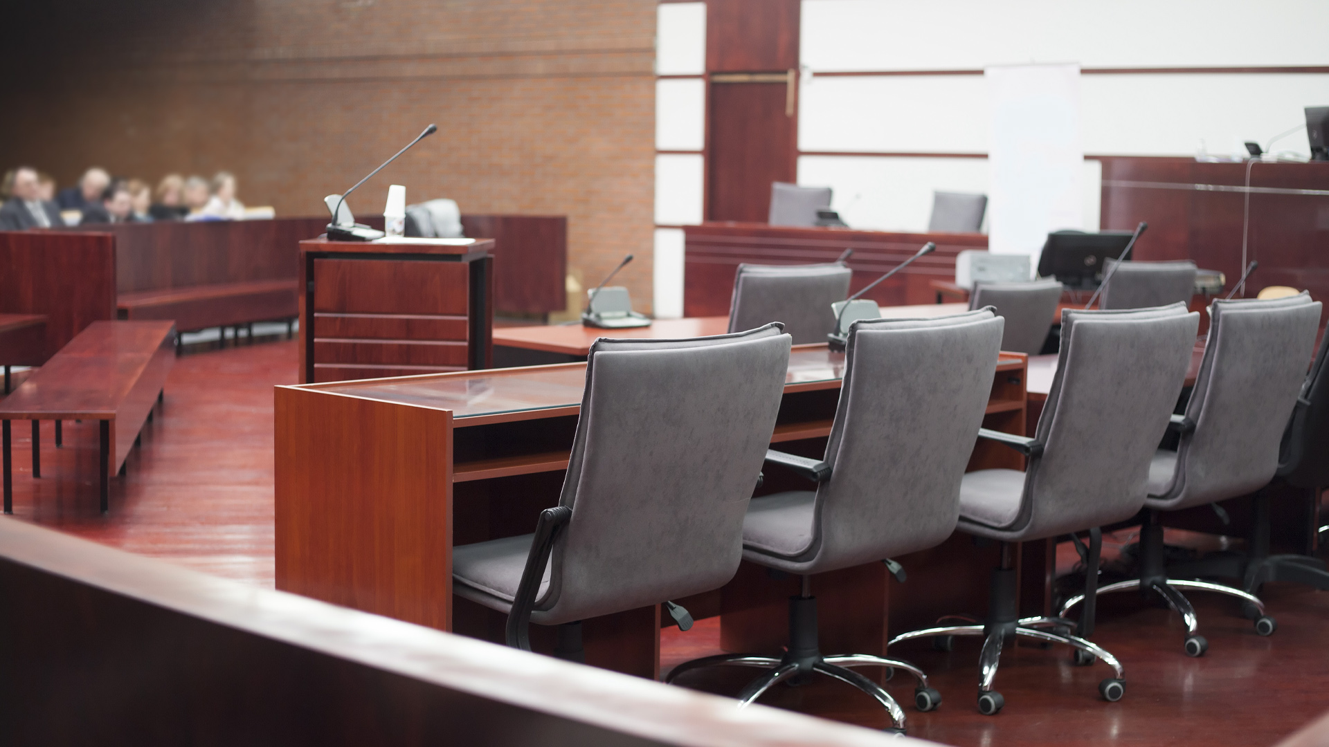 Une salle de palais de justice vide. On y voit des rangées de sièges et des micros.