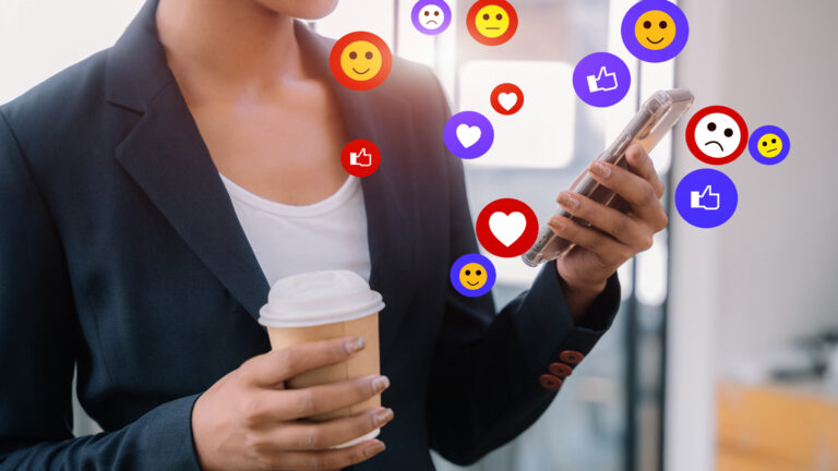 Femme d'affaires qui tient un téléphone portable avec des émojis.