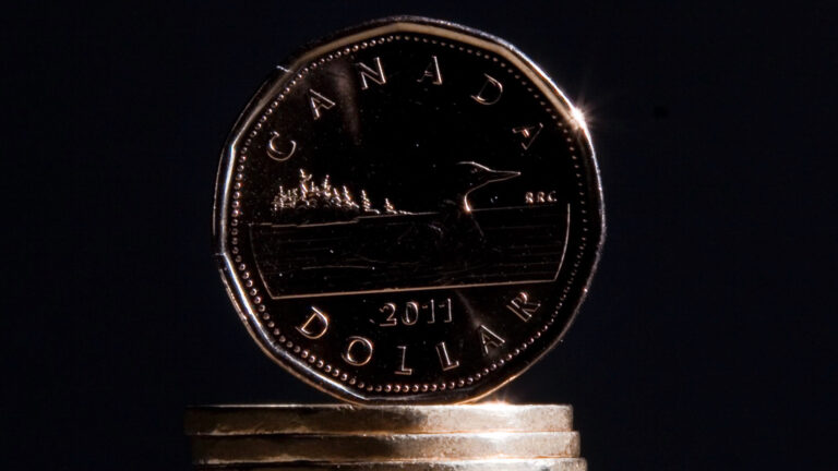 A Canadian dollar coin known as the loonie sitting atop a stack of other loonies.