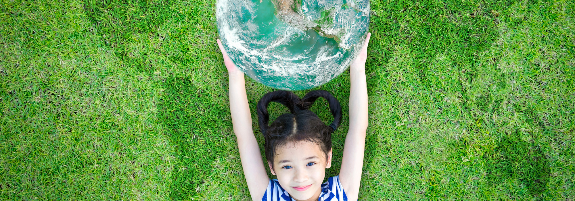 smiling-happy-healthy-little-asian-kid-holding-green-globe-lying