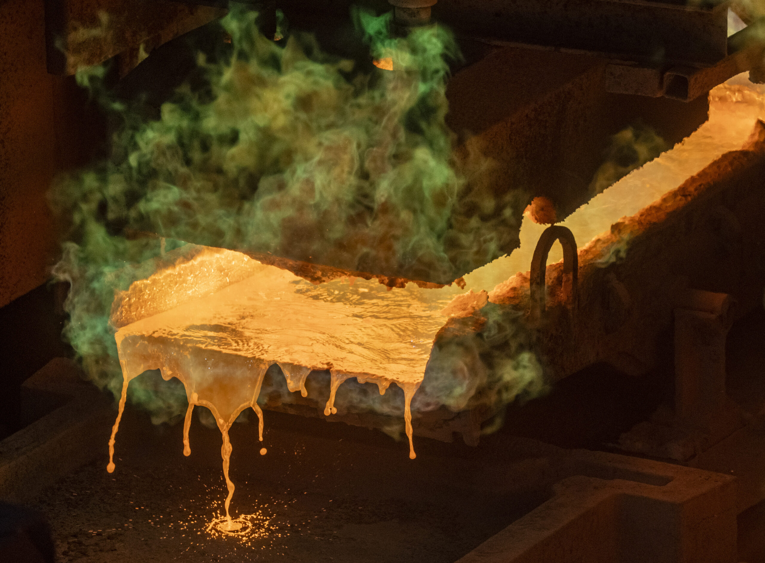 Green smoke rises of a glob of molten copper.