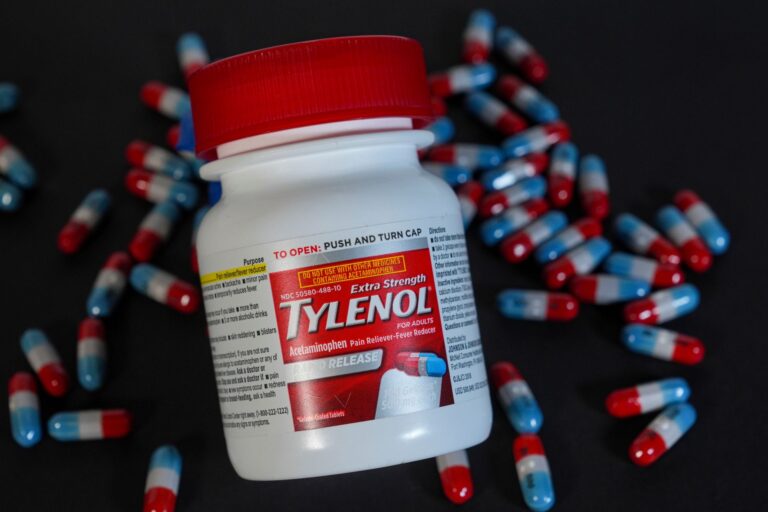 A Tylenol bottle laying on red-white-and-blue capsules.