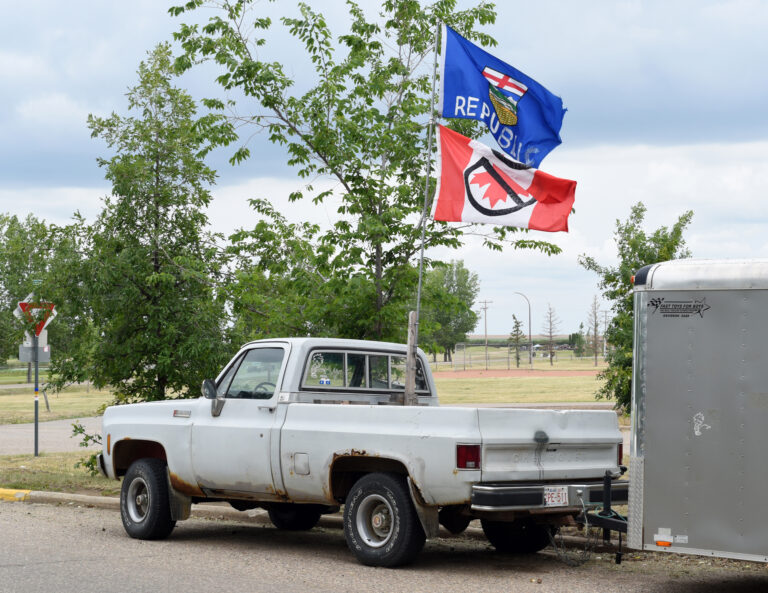 A pickup truck displays a modified Alberta provincial flag with the word "Republic" added and an upside-down Canadian flag crossed out with a "prohibition" symbol.