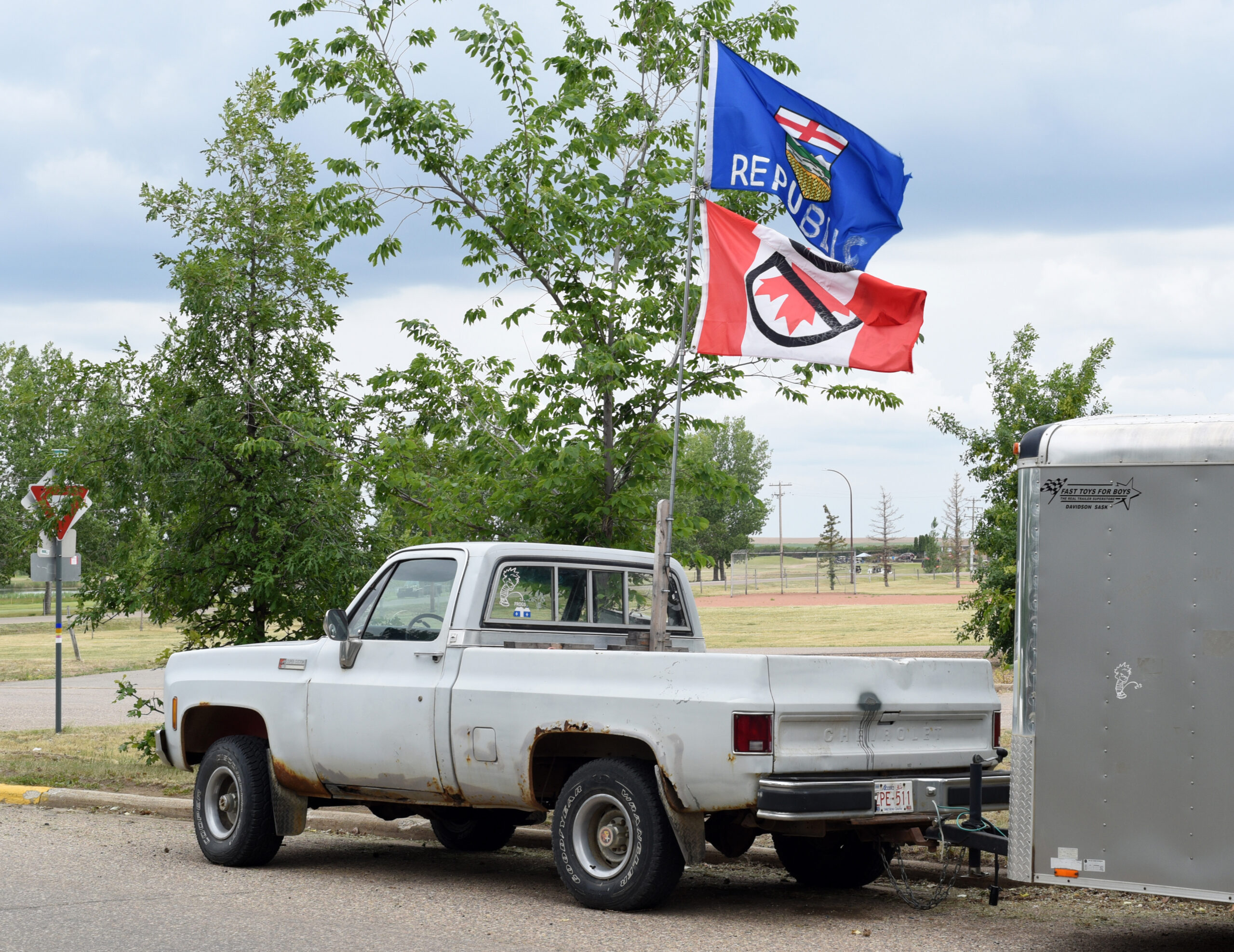 : Une camionnette arbore un drapeau provincial de l’Alberta modifié avec le mot « République » ajouté et un drapeau canadien à l’envers barré d’un symbole « interdiction ».