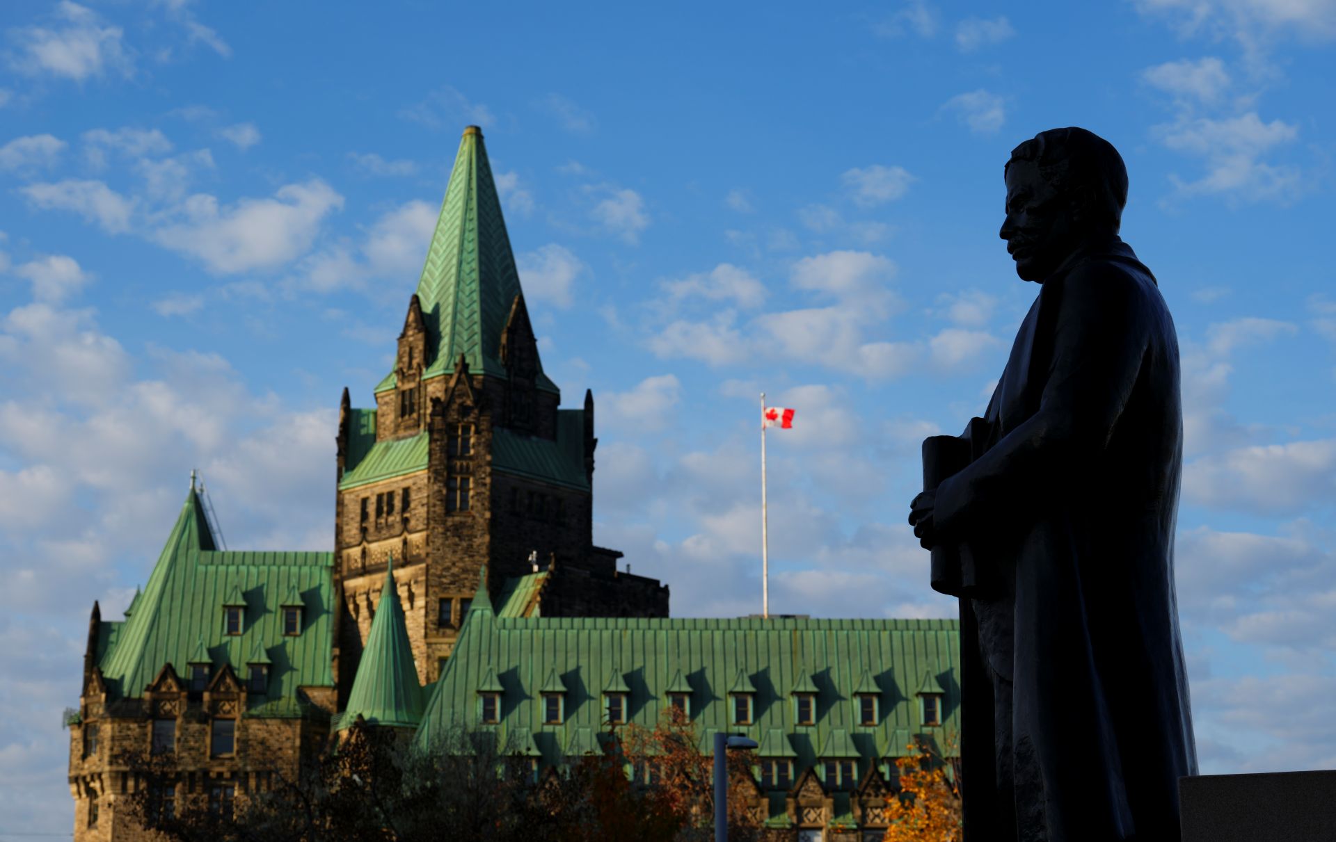 A statue of former Prime Minister Sir Robert Borden is backlit in front of the Confederation Building on Parliament Hill.