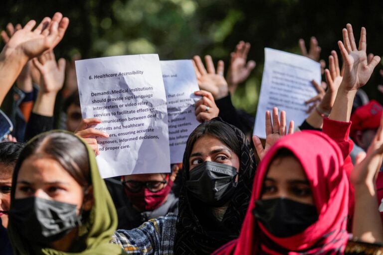Above their heads, they hold sheets of paper that outline calls for health-care accessibility.