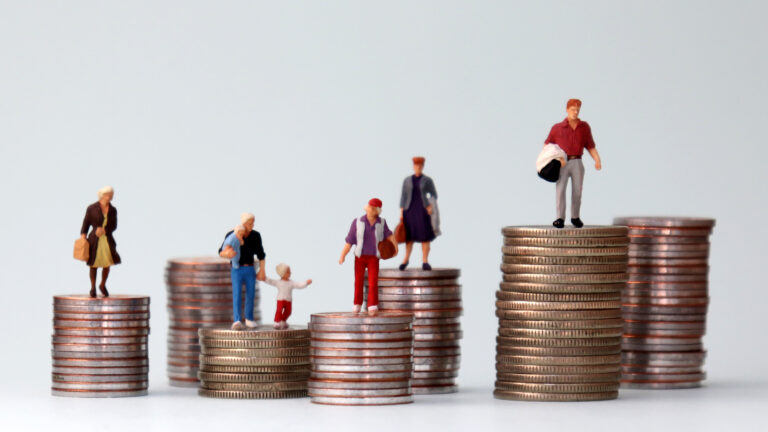 : Des figurines miniatures debout sur des piles de pièces de différentes hauteurs. Un concept illustrant les inégalités économiques.