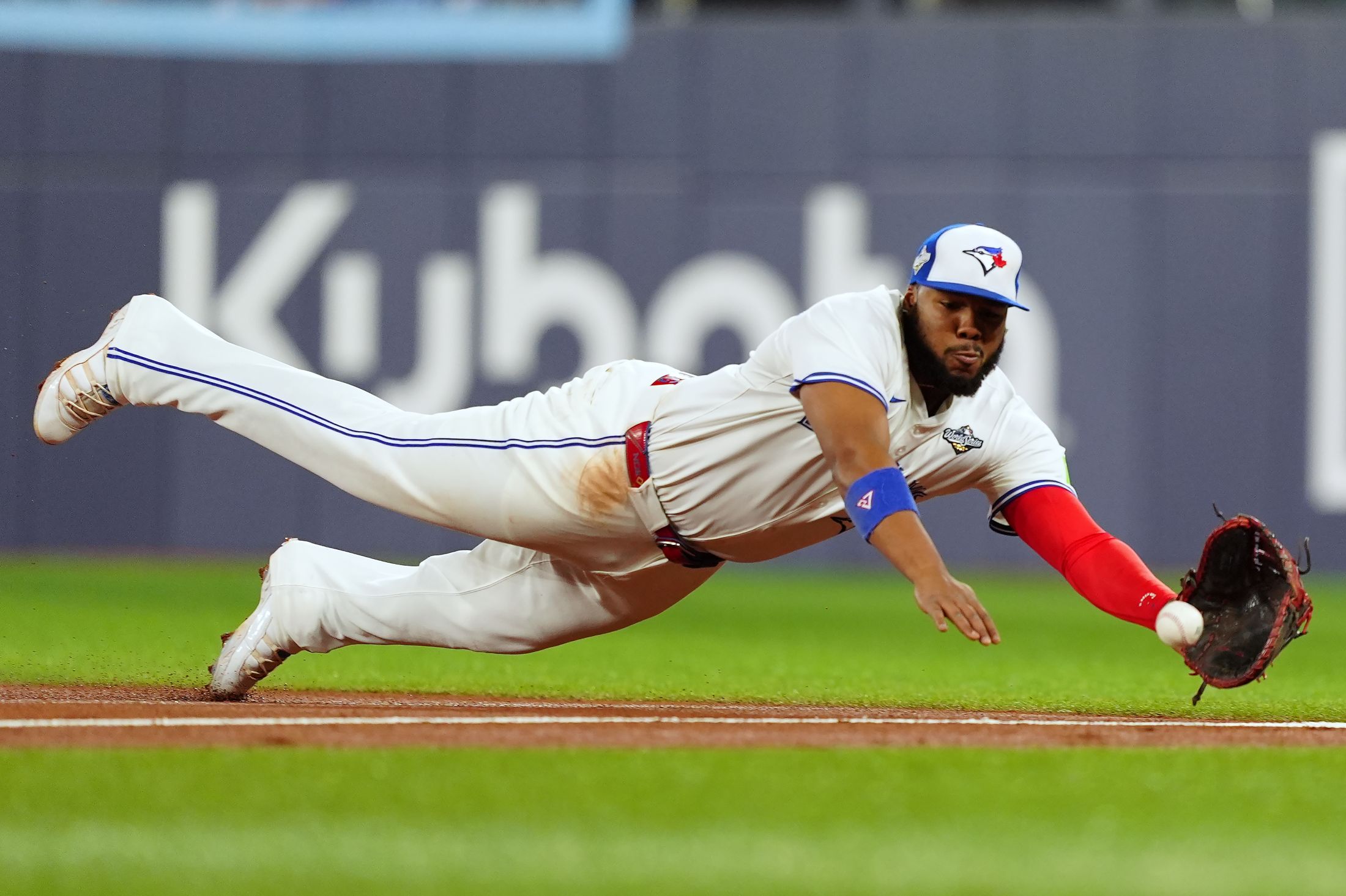 Vladimir Guerrero Jr. dives with an outstretched glove to catch a ball.