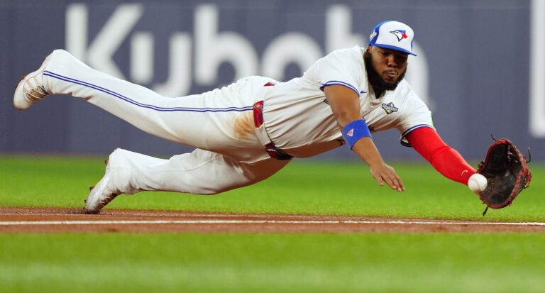 Vladimir Guerrero Jr. dives with an outstretched glove to catch a ball.