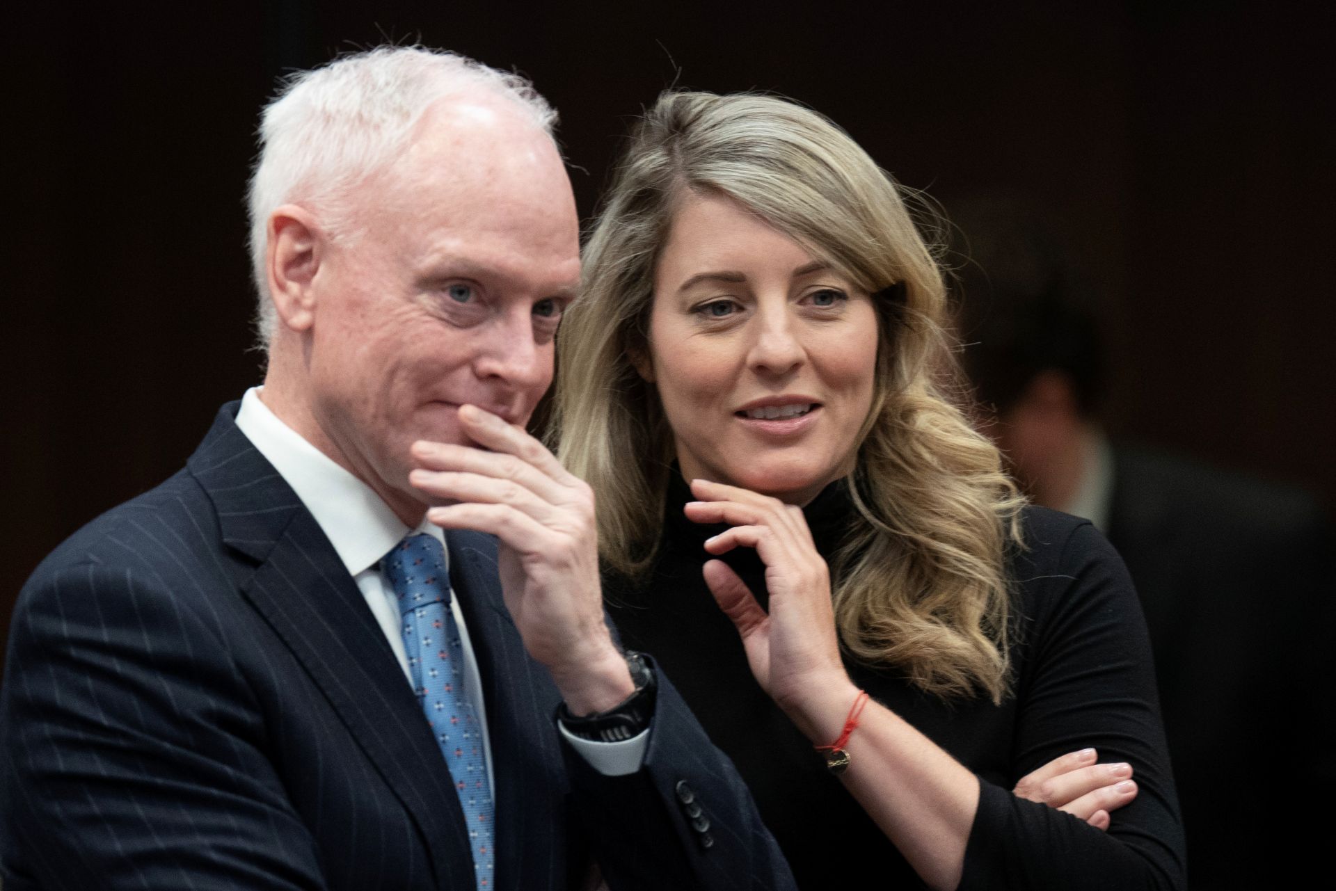 Morrison and Joly appear to be sharing a whimsical word, each smiling with a hand at their chins. 