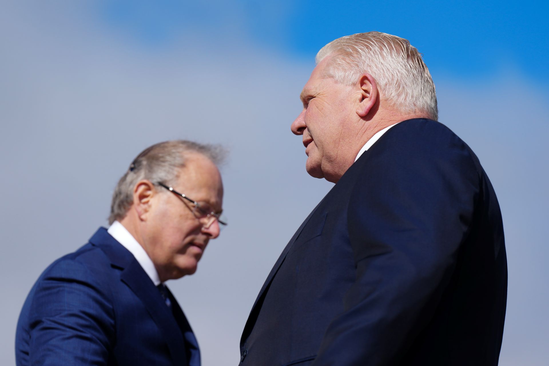 Ontario Premier Doug Ford and Solicitor General Michael Kerzner shot in profile against a blue sky.