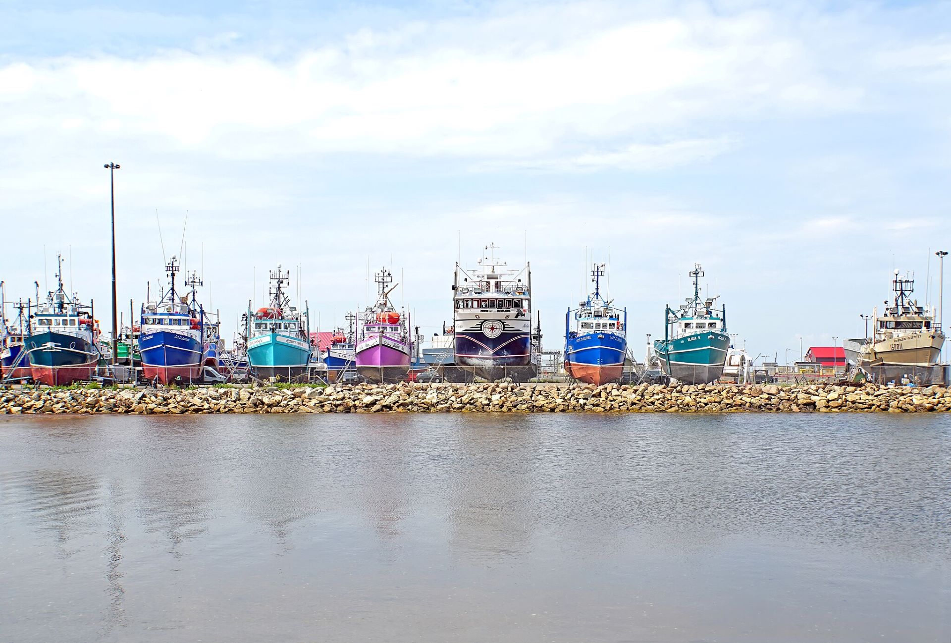 A row of boats sits in cradles along the shore.