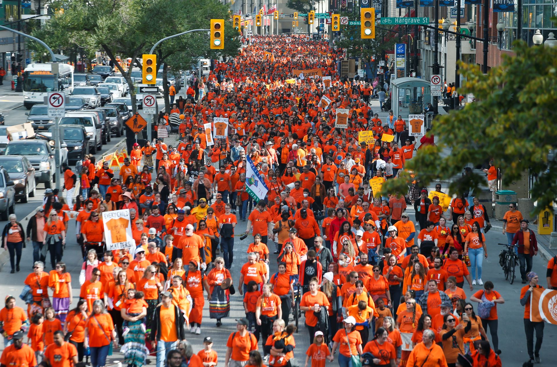 Hundreds of people fill the street, all of them wearing orange shirts.