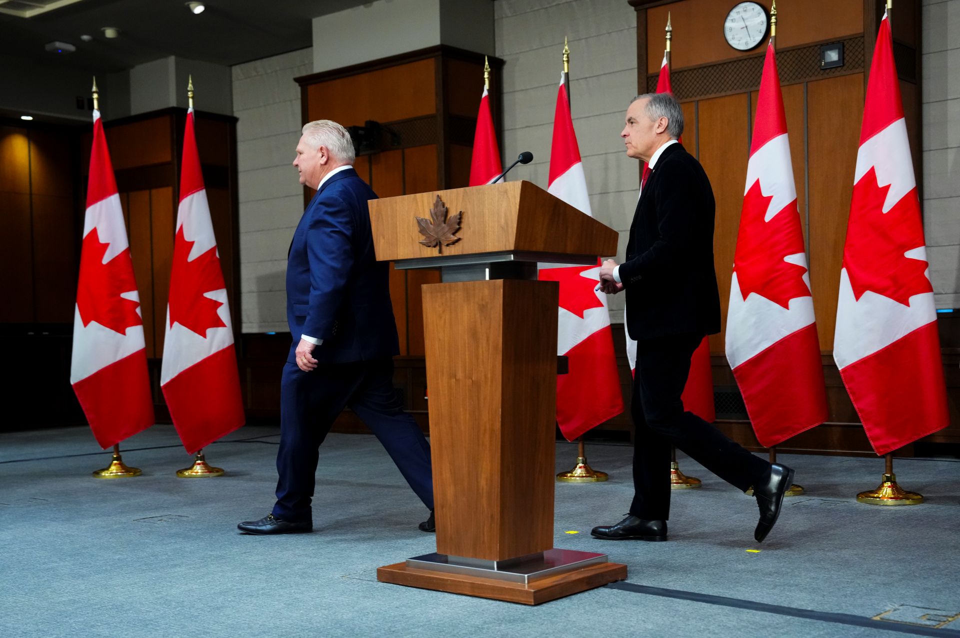 Ontario Premier Doug Ford leads Prime Minister Mark Carney off stage to the right leave following an announcement on Parliament Hill in Ottawa.