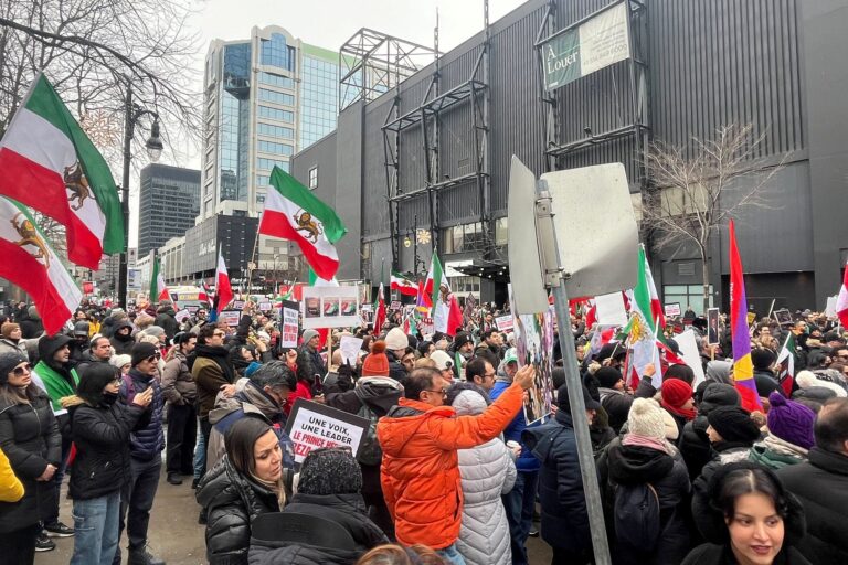 A large crowd waving flags on a downtown Montreal street.